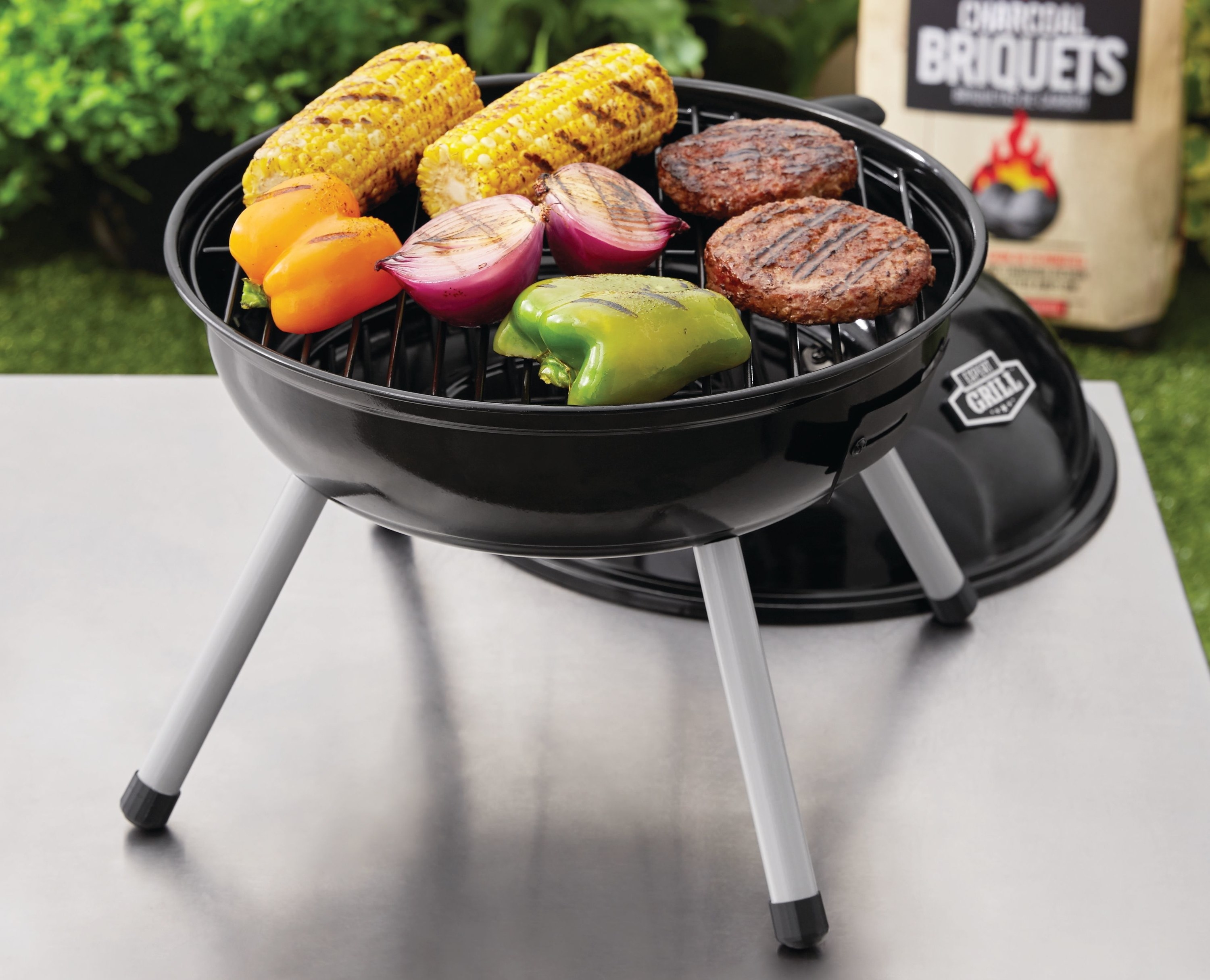 the charcoal grill on a table, grilling patties and veggies