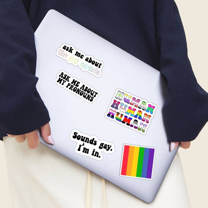 a model holds a laptop covered in stickers from the pride sticker pack