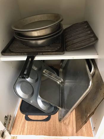 Reviewer's unorganized cabinet before using pots and pans holder
