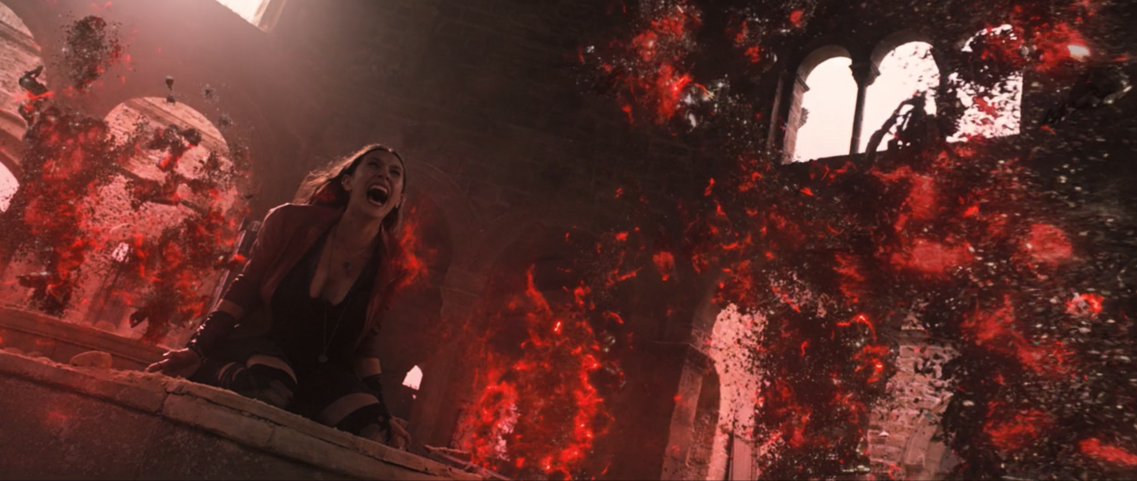 Wanda Maximoff falls to her knees as an explosion of red energy destroys the robot army around her.