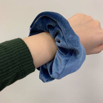 a reviewer holding out their wrist with a blue scrunchie on their list 