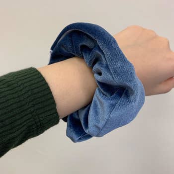 a reviewer holding out their wrist with a blue scrunchie on their wrist 