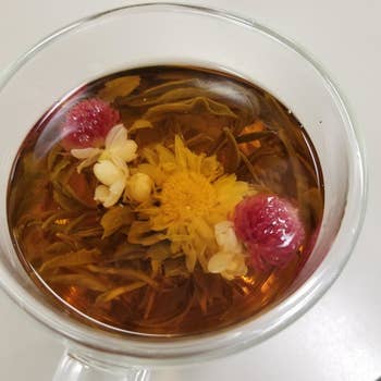 a topdown view of a mug with tea and a blooming flower inside 