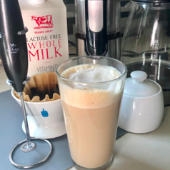 A customer review photo of the Zulay Original Milk Frother next to a frothy cup of coffee.