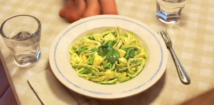 A screenshot of the trenette al pesto pasta from Luca, it has long thin noodles with green beans , yellow potato, and a sprig of basil on top