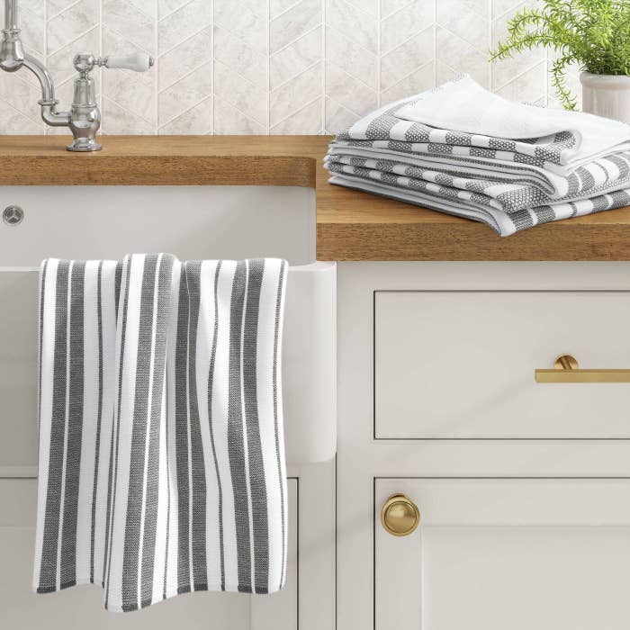 the gray striped towels on a counter and hanging on the edge of a sink