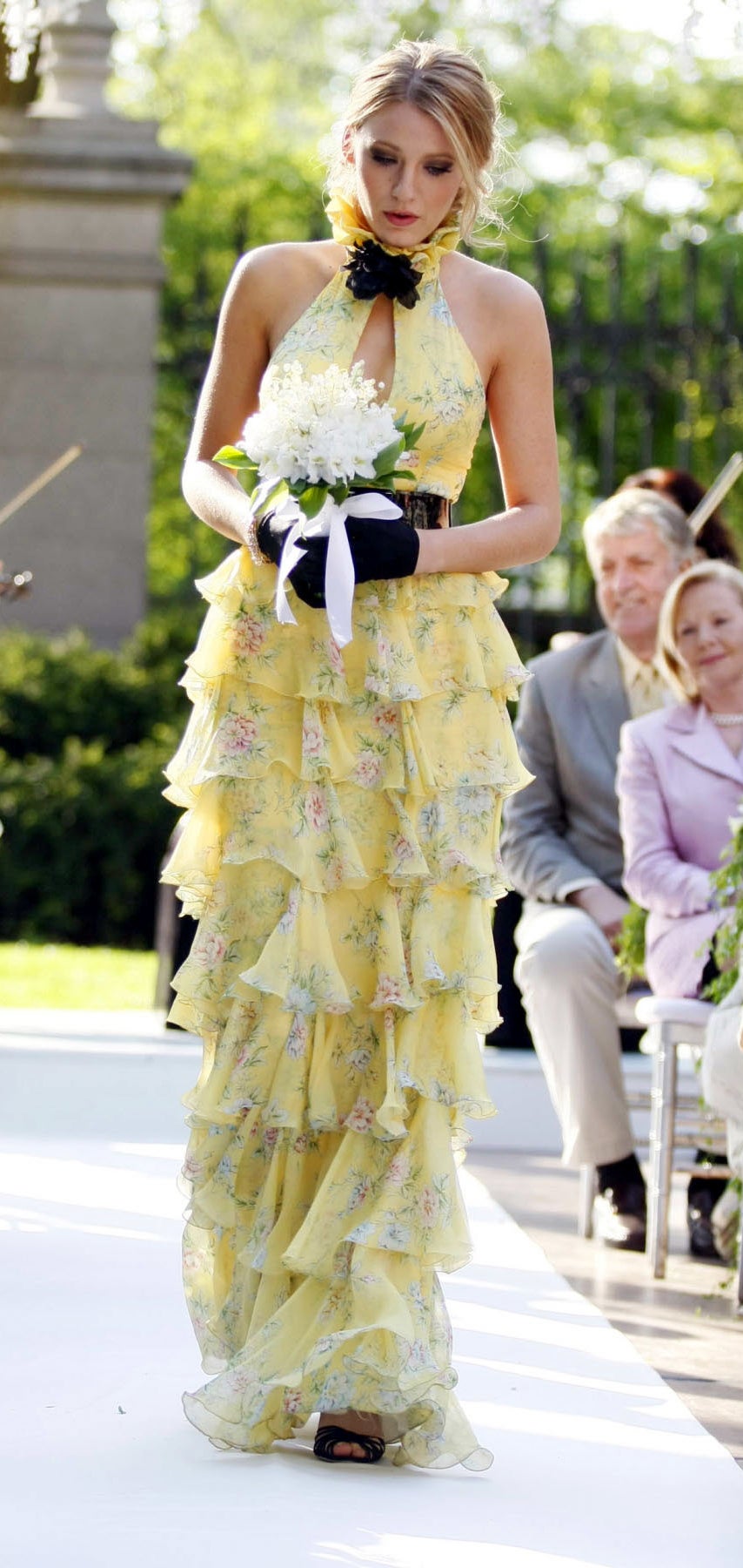 Serena in a long ruffled gown with a tiny floral print and a halter top with flowers at the neck and a big keyhole at the chest