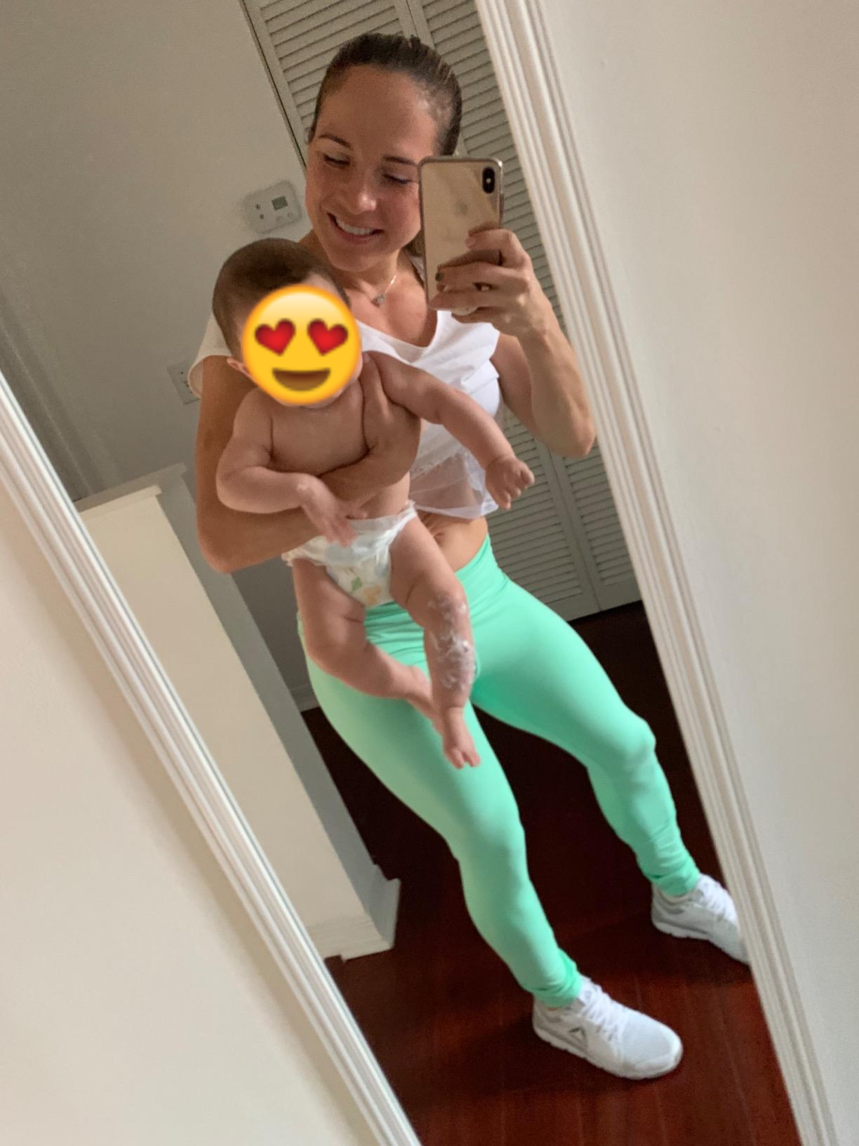 Reviewer wearing the legging in mint and holding a baby