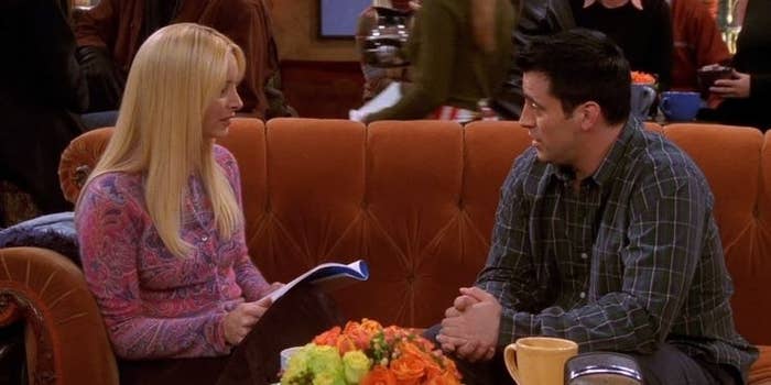 Joey and Phoebe sit on the orange couch of the Central Perk coffee shop.