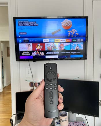 buzzfeed editor holding the firestick remote in front of her TV