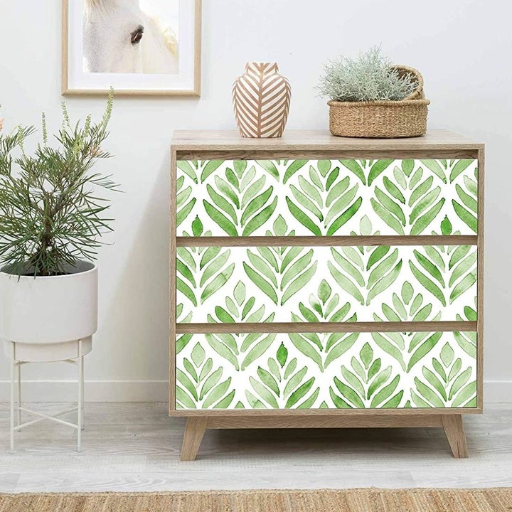 The leaf-patterned wallpaper on a set of drawers