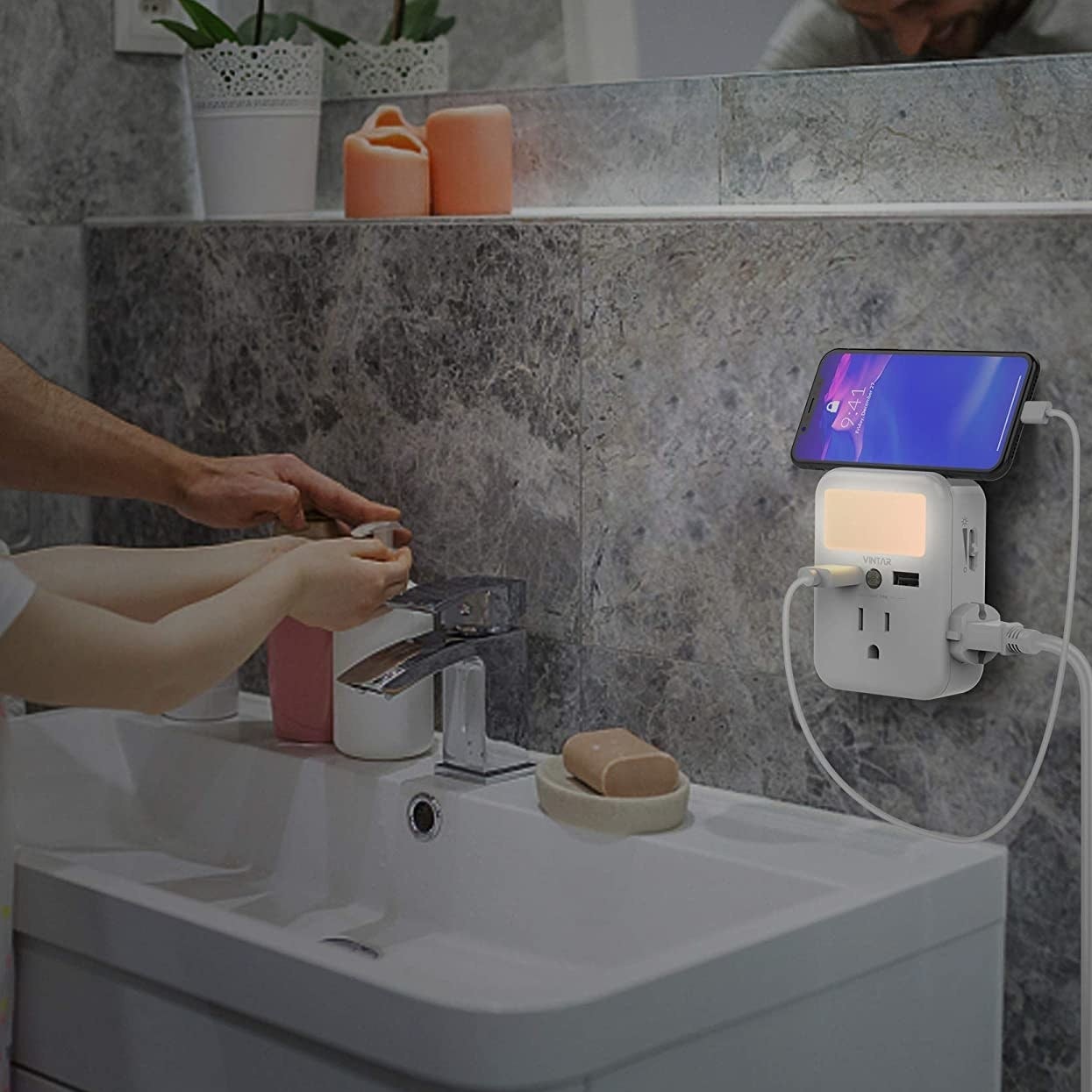 The charging hub plugged into a bathroom wall outlet; a phone is perched on the built-in shelf