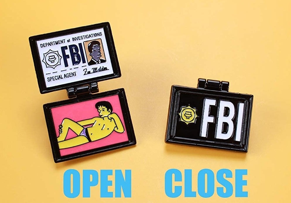 The open pin showing an ID card nd a portrait of a yellow cartoon man in their underwear with text reading &quot;open&quot; and the pin closed with &quot;FBI&quot; on the front and text reading &quot;close&quot; 
