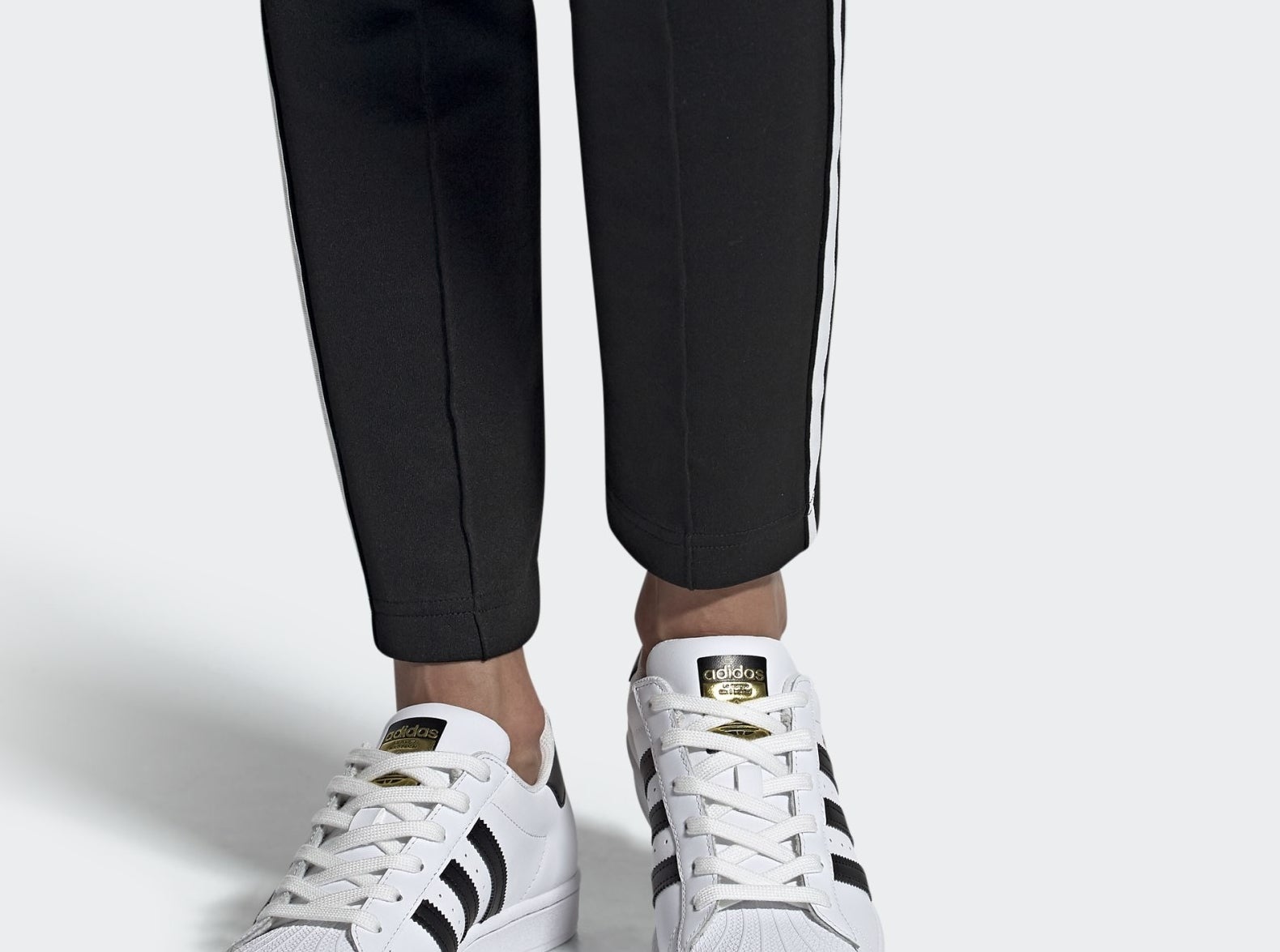 model wearing the white superstar adidas sneakers with black stripes