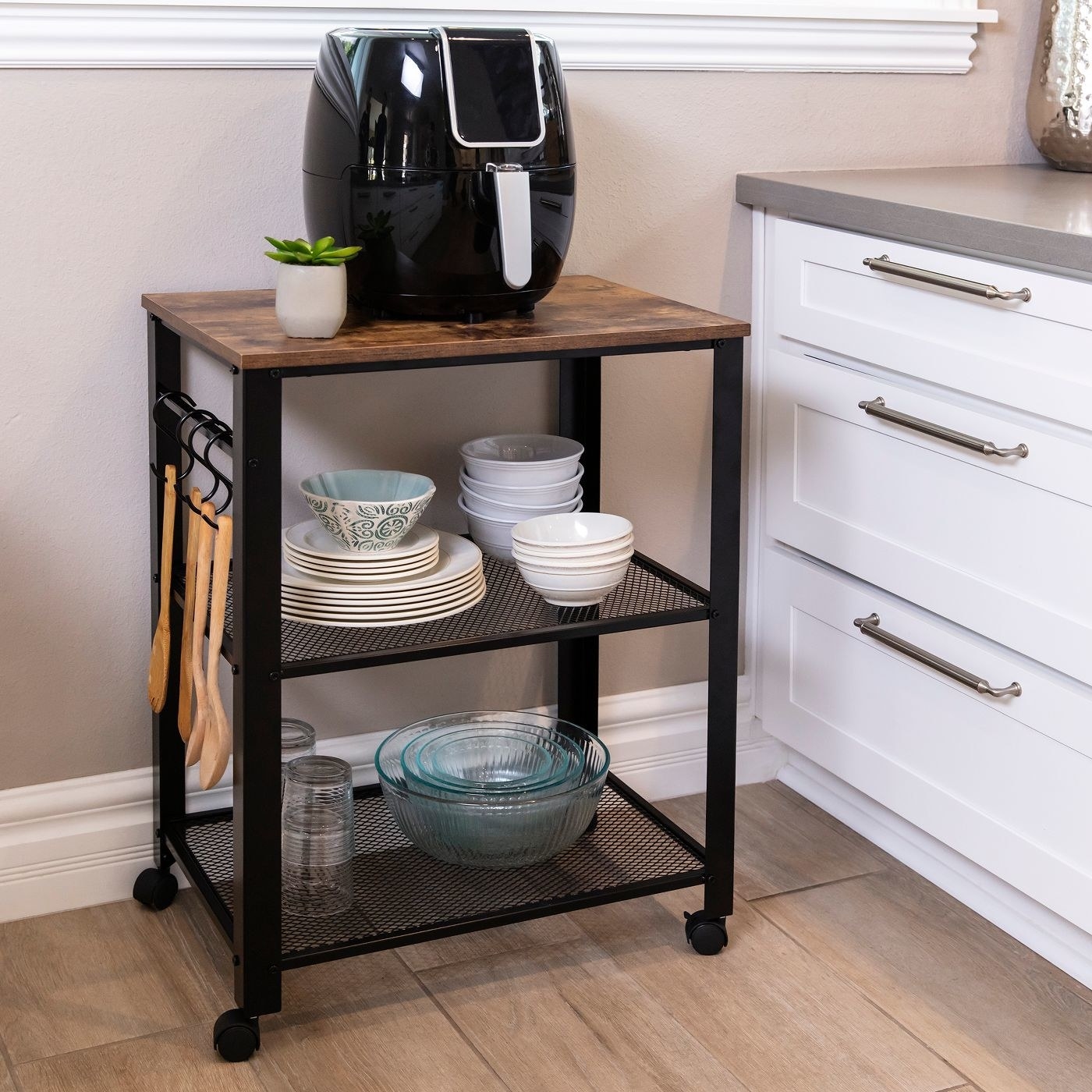 the black metal mesh and wood top cart with dishes and appliances