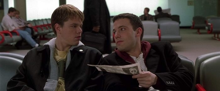 Matt Damon and Ben Affleck sitting in an airport terminal 