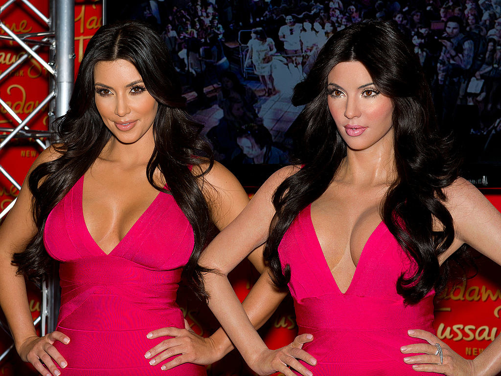 Kim Kardashian standing next to her wax figure wearing the same pink dress as it