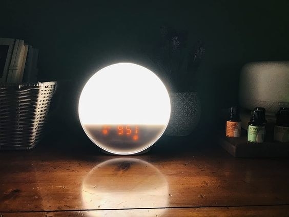 a digital alarm with a natural glow that&#x27;s sitting on a bedside table