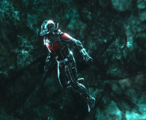 Ant-Man, in a miniature size, looks around at the green tinted world of the Quantum Realm.