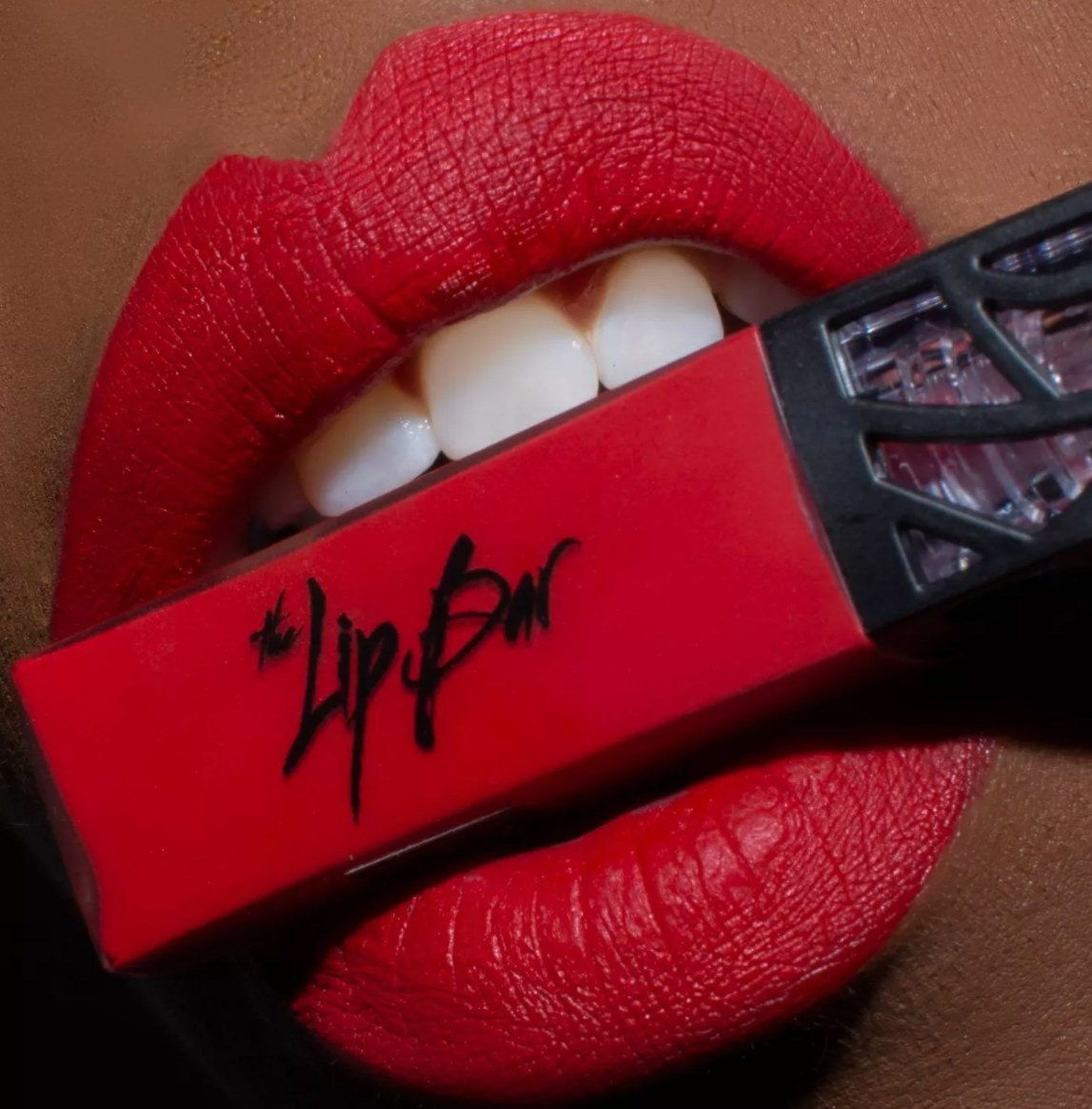 model holding Lip Bar lipstick between lips