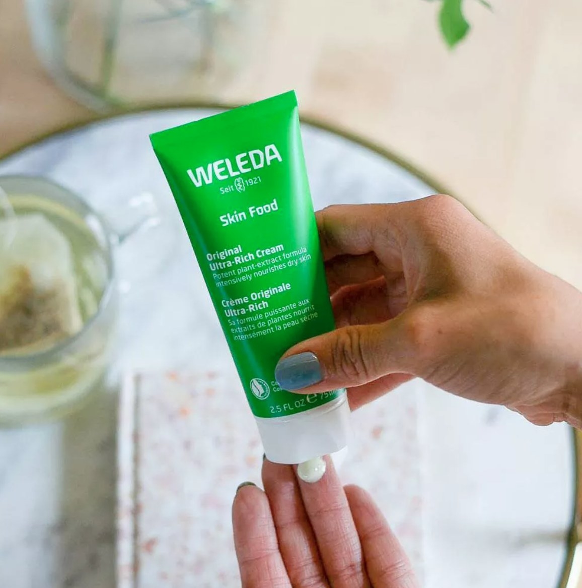 hand squeezing out drop of weleda skin cream