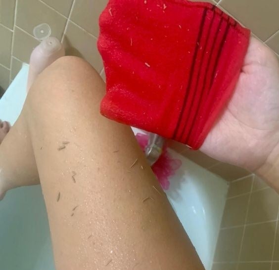 Reviewer exfoliating their leg with the Korean towel