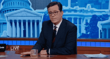 Stephen Colbert sits at his desk and taps his fingers