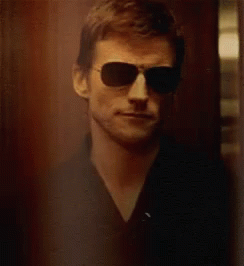 Deucalion leaning against a wooden door, looking dubious.