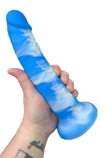 Model holding large blue and white cloud-patterned dildo