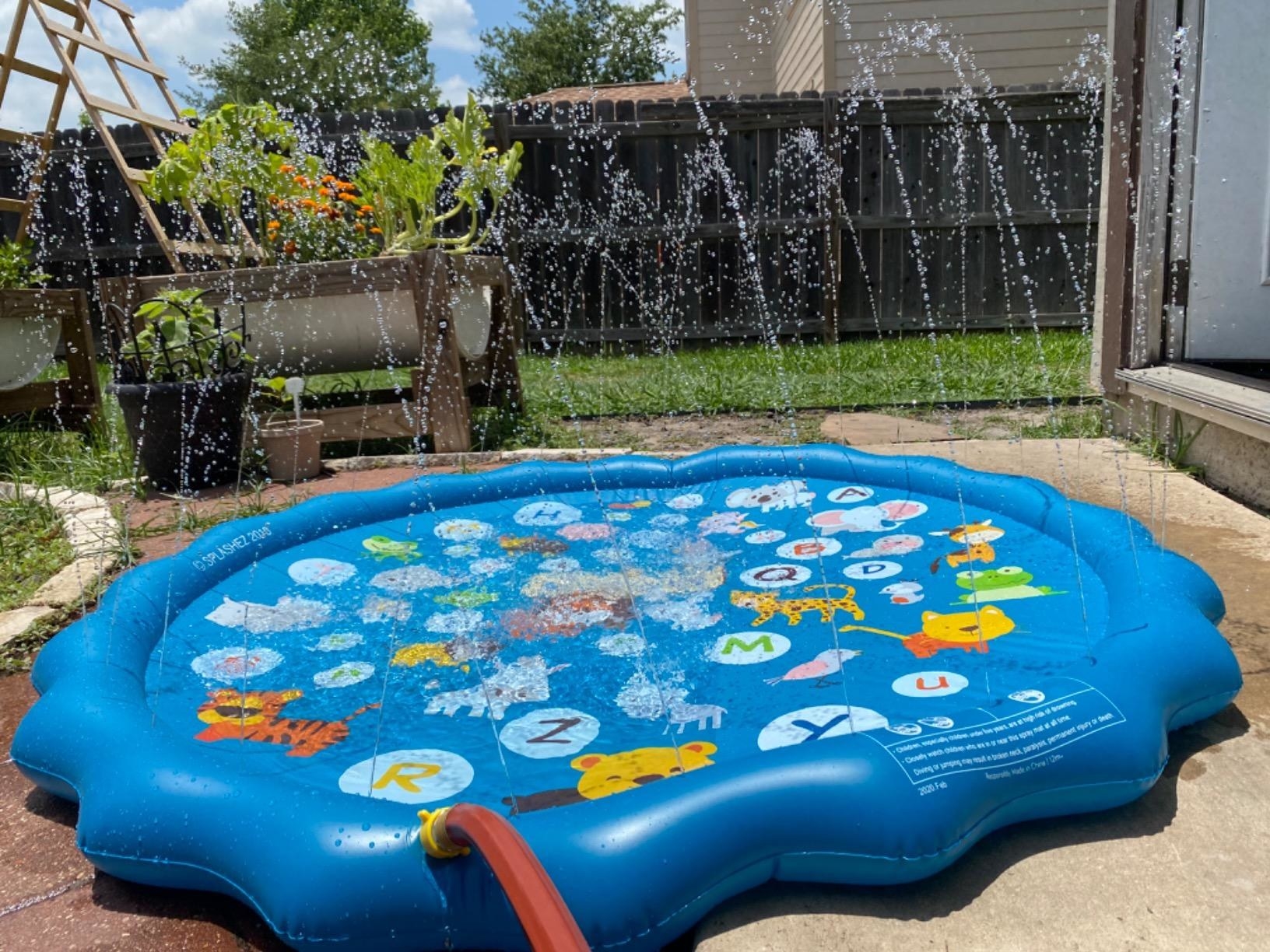 Reviewer photo of the blue splash pad with an alphabet pattern and water shooting out from it