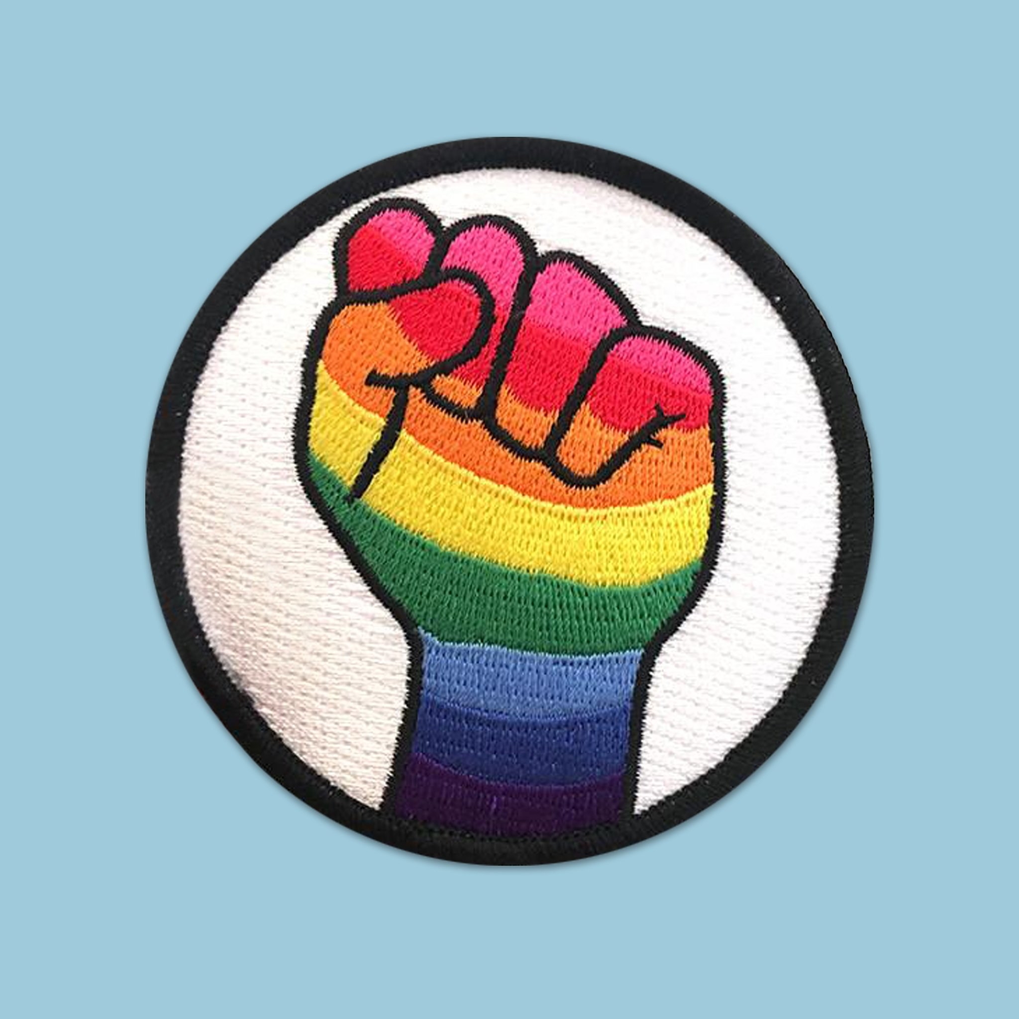 the rainbow fist patch in front of a sky blue background