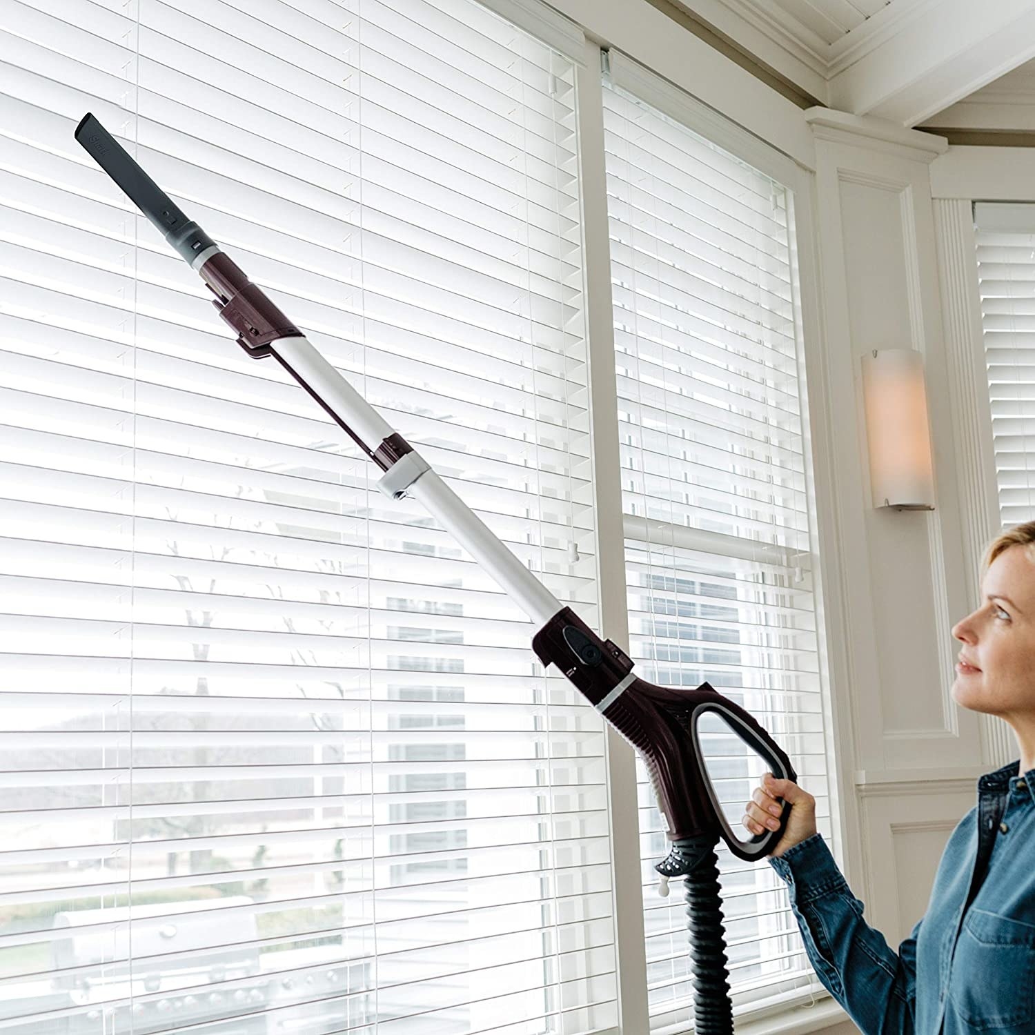 long necked vacuum with handle being used to clean blinds