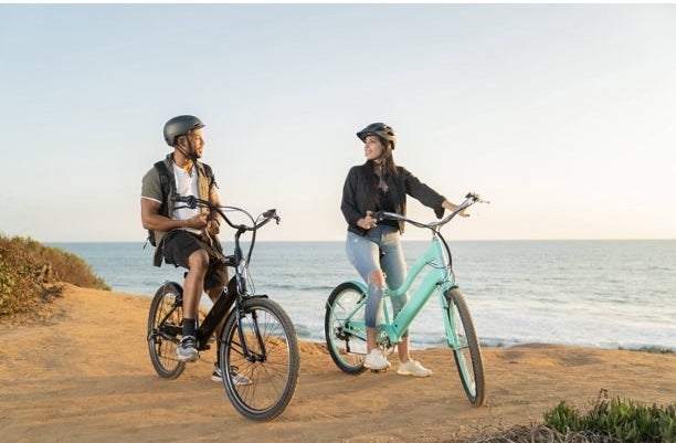 two people on bikes riding by the beach