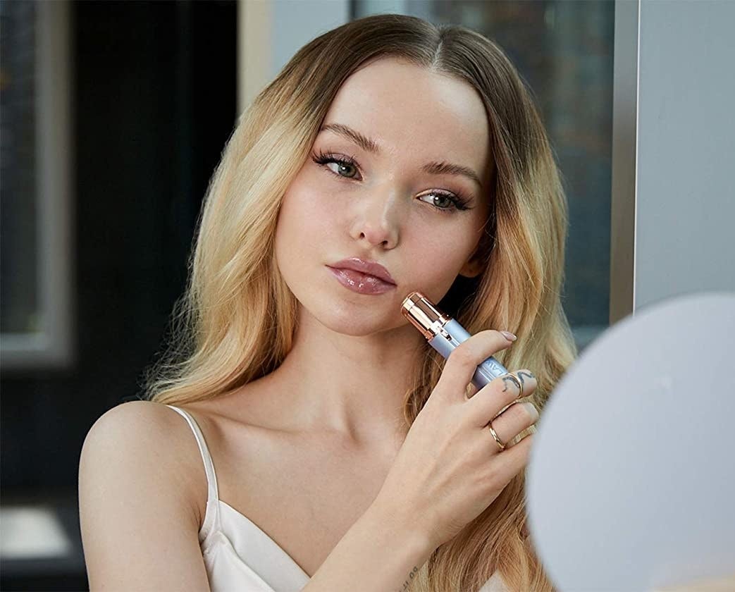 A person using the tool to remove peach fuzz from their face