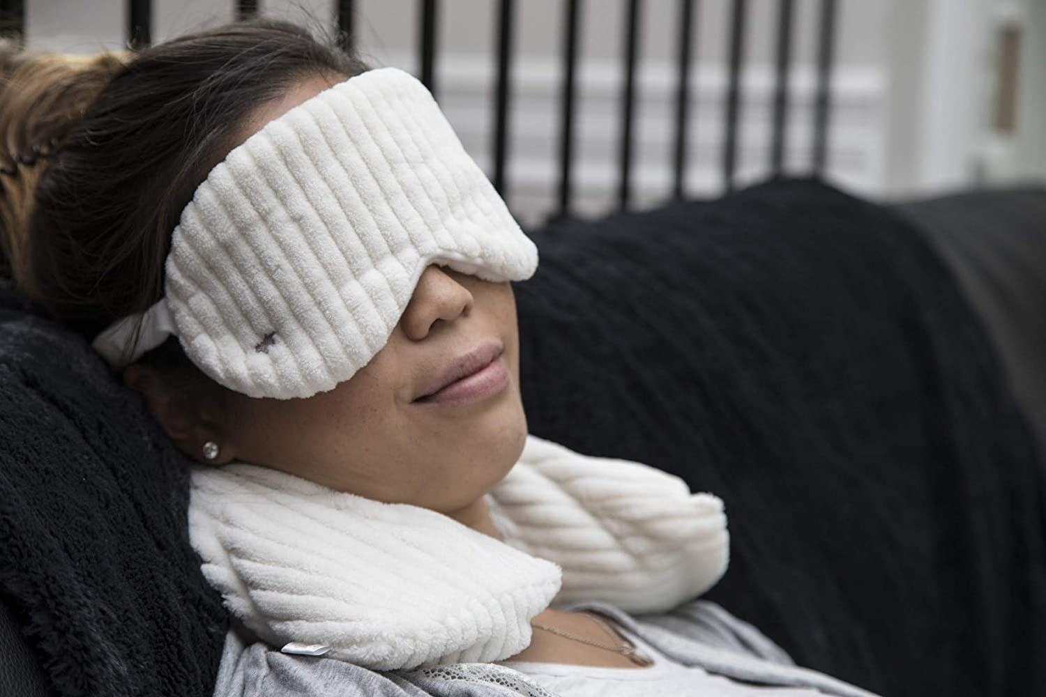 A person snoozing on a couch while wearing the plush eye mask