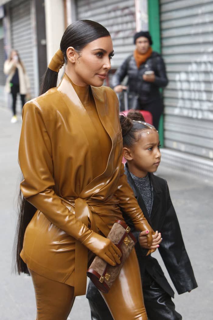 Kim Kardashian and North West walk down a sidewalk