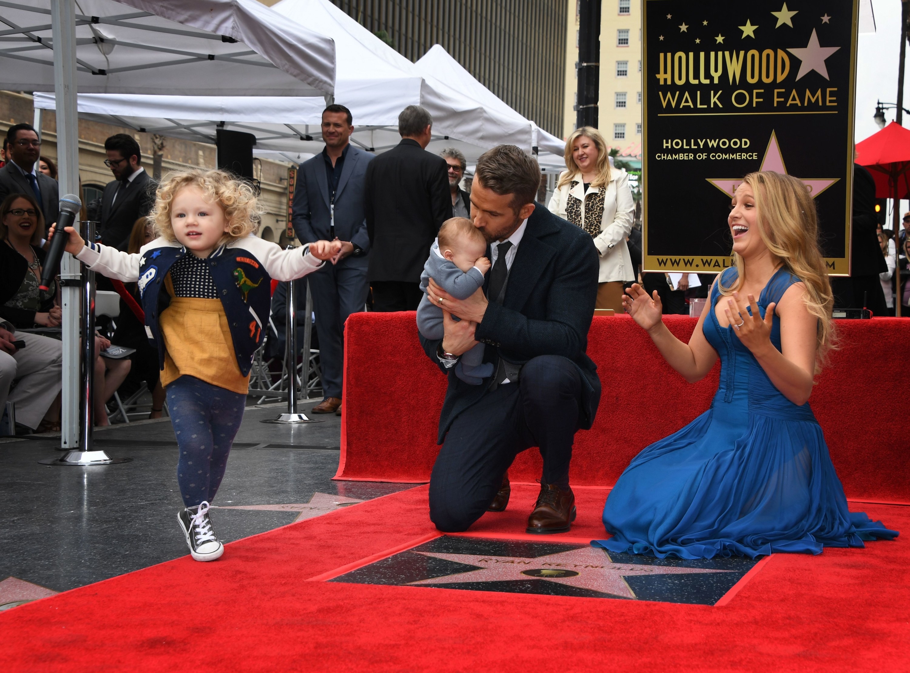 Actor Ryan Reynolds (C) kisses his unnamed new baby as his wife Blake Lively and daughter James look on during the Deadpool actors Hollywood Walk of Fame ceremony in Hollywood, California on December 15, 2016