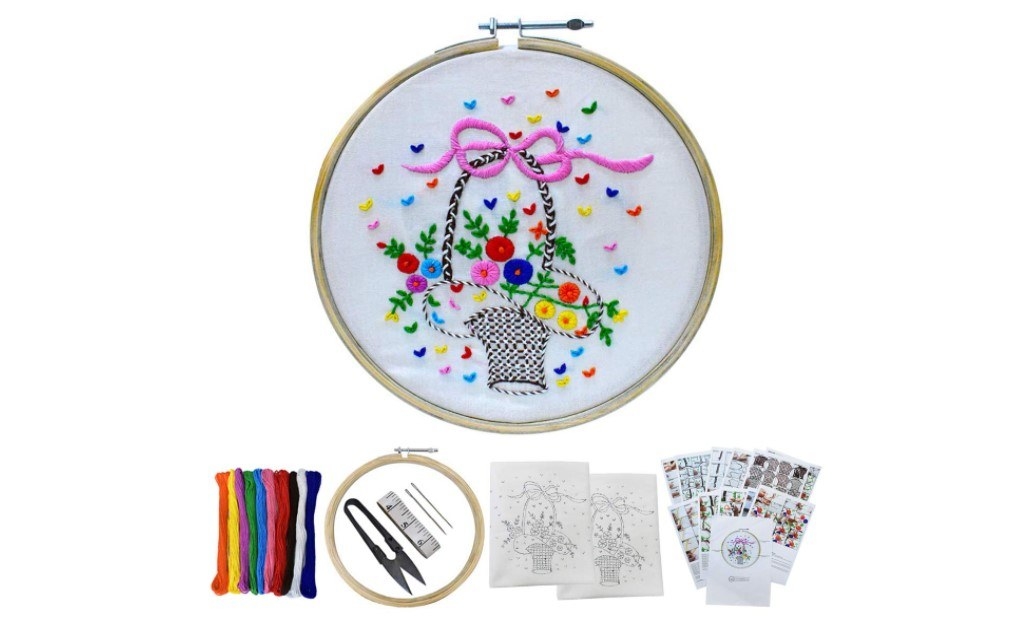 Contents of the embroidery kit laid out with a frame that has a design stitched on it.