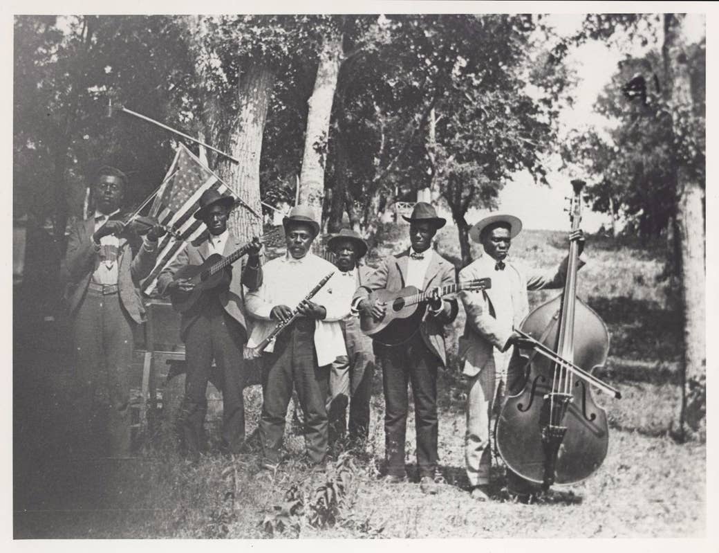 A group of men with musical instruments in a field with an American flag 