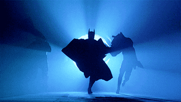 Batman, Robin, and Batgirl running in front of the bat signal