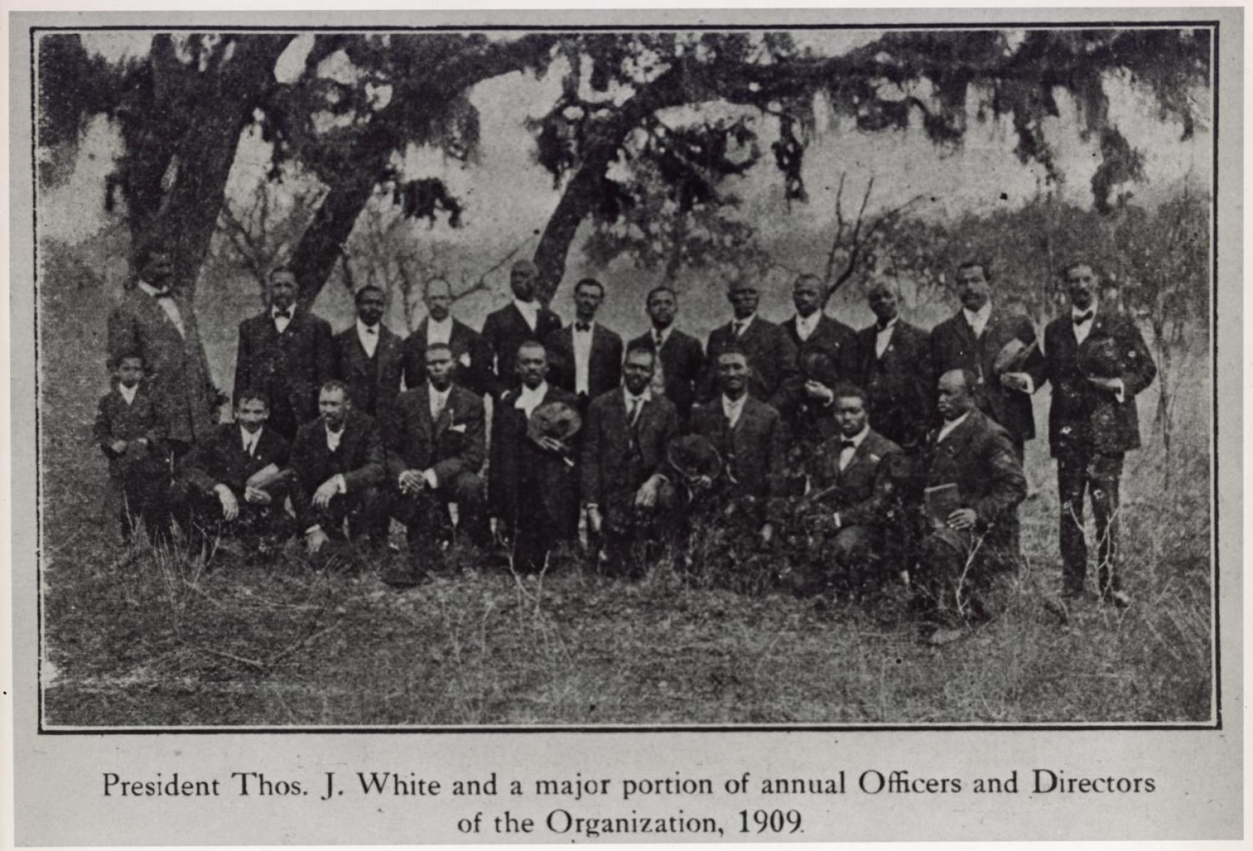 A group of men in suits posing as a group in a field