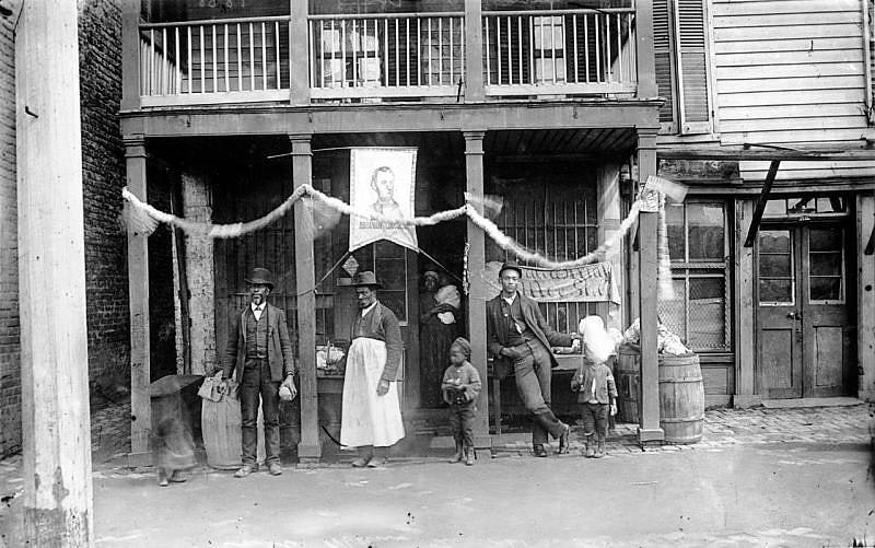 A group of men and two small boys in front of a picture of Abraham Lincoln 