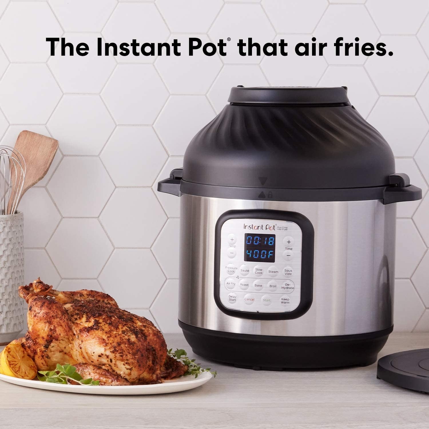 Instant Pot Duo Crisp placed on table with plate of cooked chicken on the side