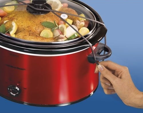 a model closing the red slow cooker lid