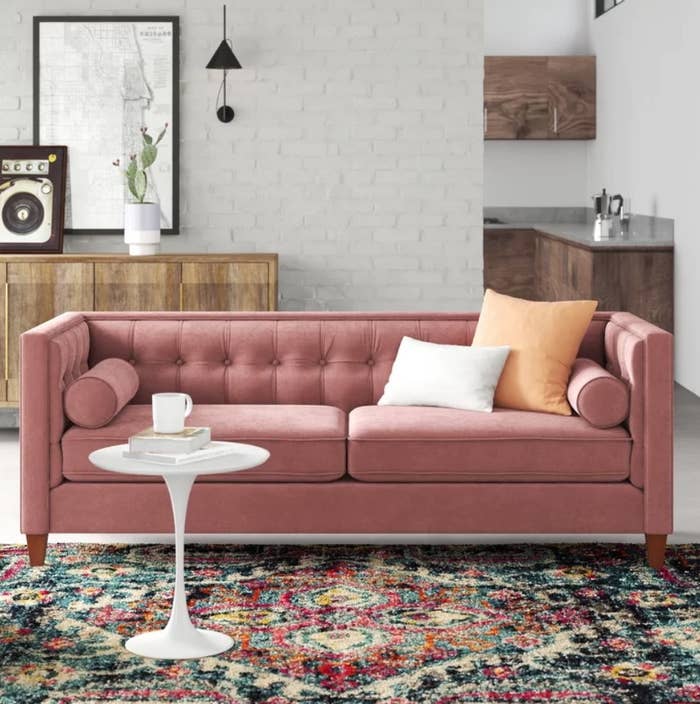 An ash rose, velvet sofa with reversible cushions displayed in a living room 