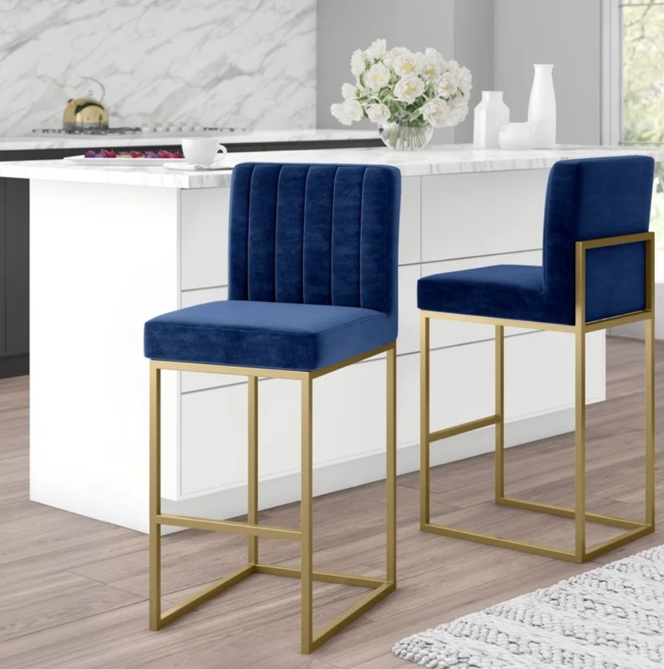 A navy upholstered bar stool with gold finishing at the kitchen counter