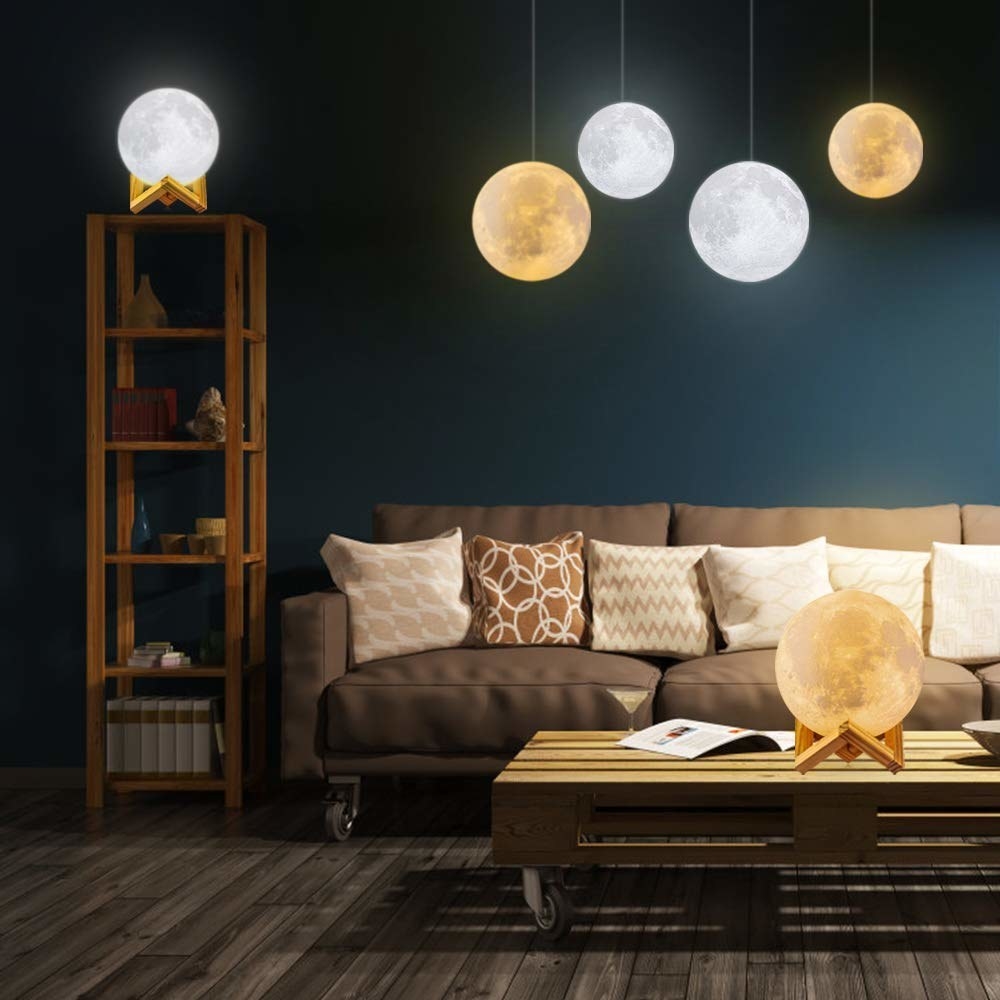 Moon lights hanging from the ceiling and sitting on the table and shelf of a living room.
