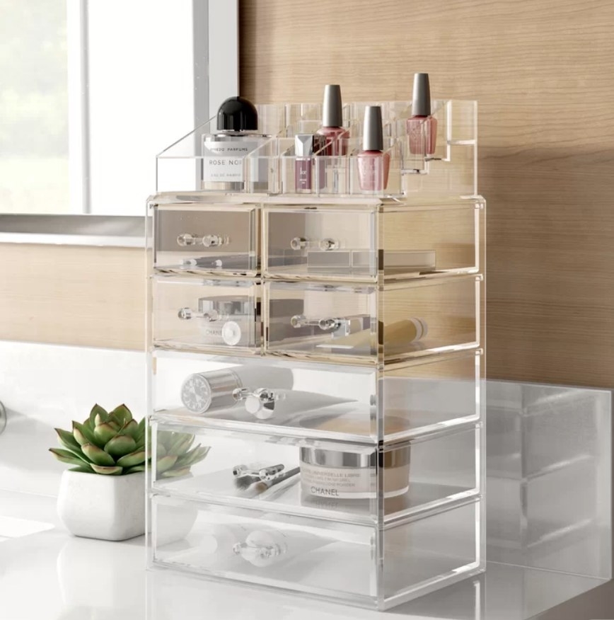 A freestanding, acrylic makeup organizer with seven drawers and two pieces atop for polish, brushes, and more