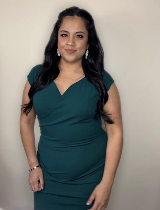 A reviewer wearing a green body con dress