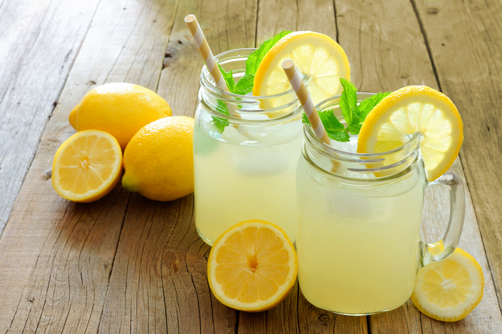 Two glasses of lemonade surrounded by lemons